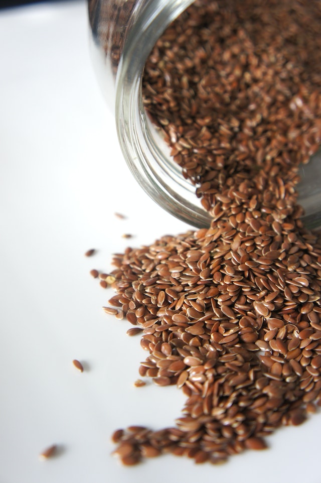 A bowl of flaxseed on a white surface.